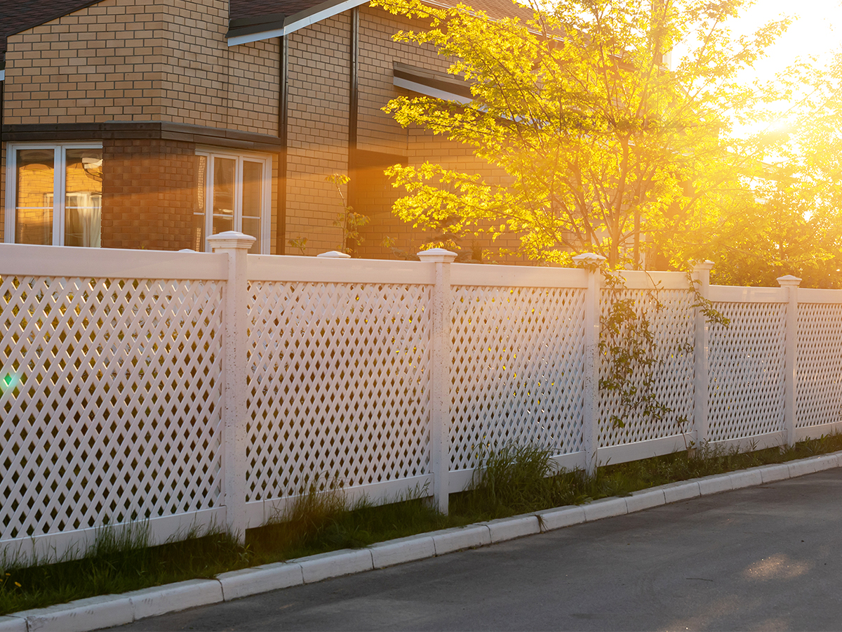 Lattice white vinyl fencing around a home at sunset